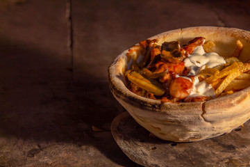 Donner in a bowl of baked bread with chicken legs, mushrooms, pickles, french fries and garlic sauce. In a stone furnace.