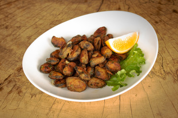 Breaded mussels with dill and garlic, garnished with lettuce leaf and slice of lemon.