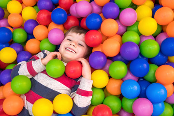 Little boy playing in dry pool with plastic balls in the nursery. Close-up leisure activities...