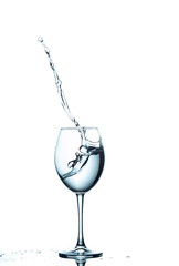 Clear Wineglass With Water Flows and Drops In Motion Against Pure White Background.