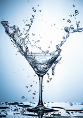 Water Splash Photography. Clear Wineglass With Burst of Water Splashes In Motion Against White Background.