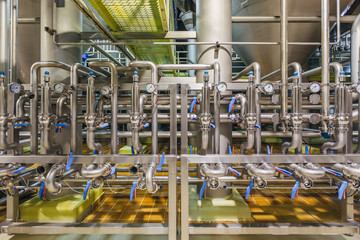 Modern brewery interior. Industrial stainless steel pipes connected with vats and control valves 