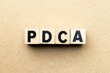 Obraz premium Alphabet letter block in word PDCA (business abbreviation of plan do check act) on wood background