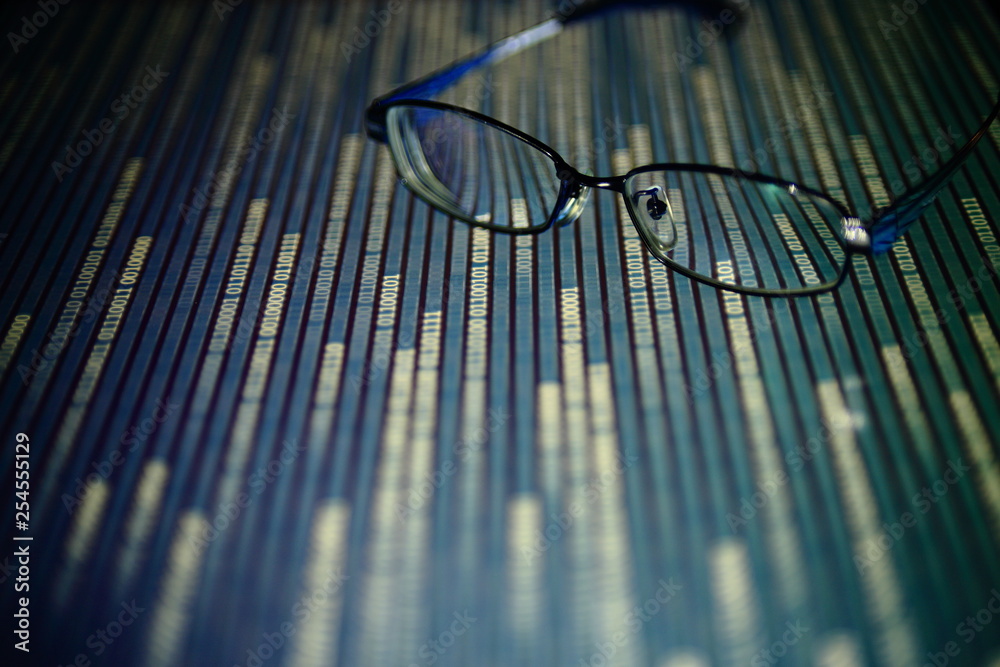 Poster big data analysis. glasses placed on a LED digital panel display white light one and zero binary text number in moving motion pattern. modern technology blue block grid pattern backgrounds