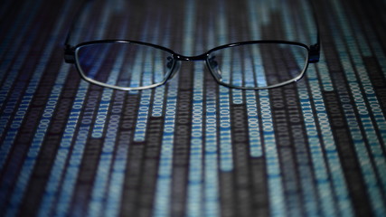 big data analysis. glasses placed on a LED digital panel display white light one and zero binary text number in moving motion pattern. modern technology blue block grid pattern backgrounds