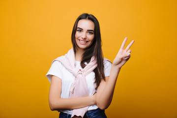 Beautiful young caucasian woman looking at camera and showing peace with a hand isolated on yellow...