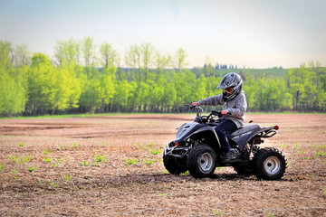 A young boy quading in a spring field
