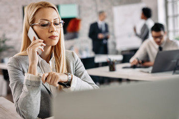 Serious businesswoman making a phone call while working in the office.