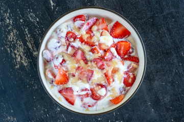 Red strawberry and white yogurt brulee. Fruit dessert on breakfast with wedges of perfectly ripe in season strawberry, closeup