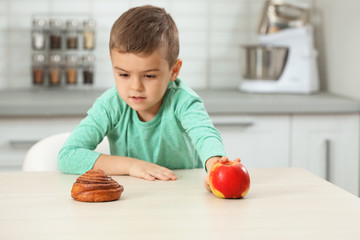 Fototapeta premium Little boy with pastry and apple at home. Diabetes diet