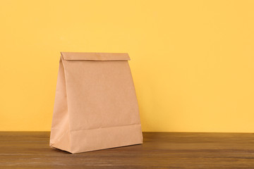 Paper bag on table against color background. Mockup for design