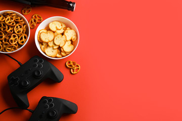 Flat lay composition with video game controllers, snacks and space for text on color background © New Africa
