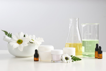 Skin care products, ingredients and laboratory glassware on table. Dermatology research