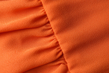 Texture of orange fabric with folds as background, closeup
