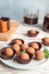 Plate with chocolate truffles on wooden table