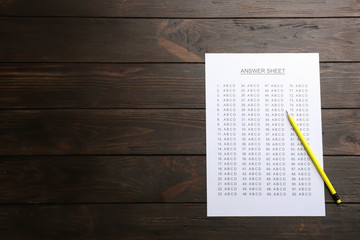 Answer sheet and pencil on wooden background, top view with space for text