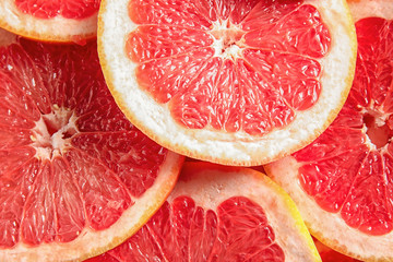 Many sliced fresh grapefruits as background, top view