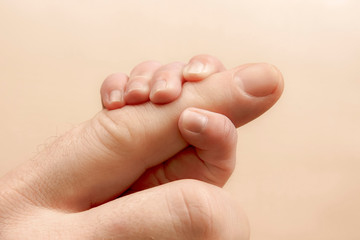Newborn baby holding his hand on the fingers of parents