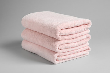 Stack of fresh towels on light background