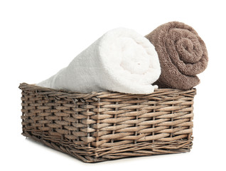 Fototapeta na wymiar Rolled soft terry towels in wicker basket on white background