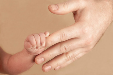 Newborn baby holding his hand on the fingers of parents