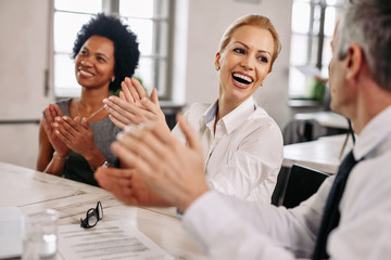 Happy colleagues applauding during a business meeting in the office.