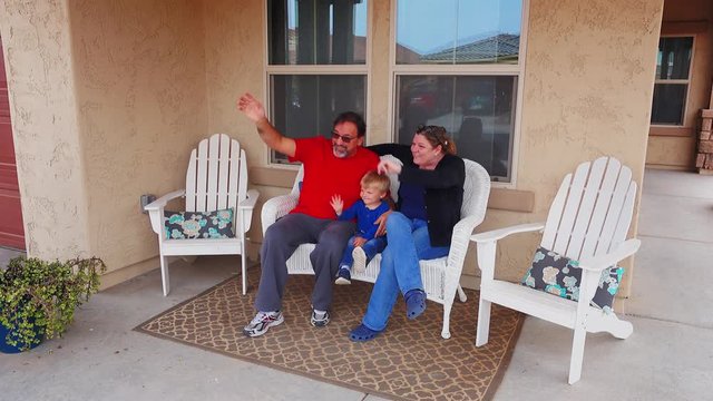 Grandparents sit on their front porch with their grandson in a typical Arizona residential neighborhood. Phoenix suburbs.  	