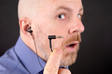 bearded man shows the plug for the earphones