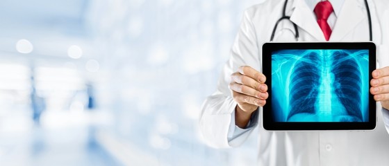 Male doctor with stethoscope with x-ray on blurred hospital background