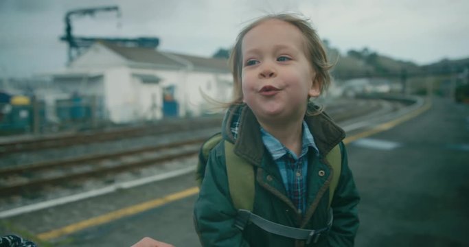 Toddler on train station platform getting help with his buttons