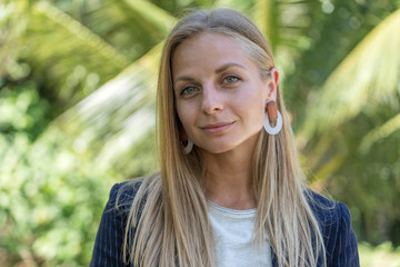 Beautiful caucasian blonde girl in a business suit in nature background. A portrait of a young business woman in tropical garden, Thailand