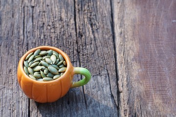 Pumpkin grain in pumpkin cup on classic old wooden table background, cereal