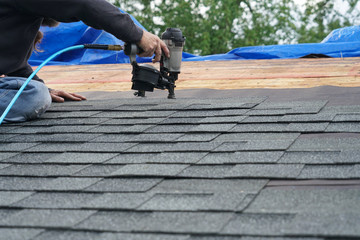 handyman using nail gun to install shingle to repair roof © nd700