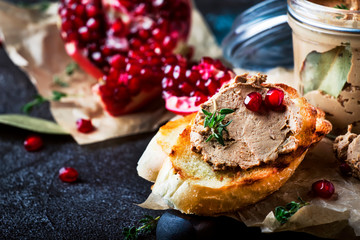 Delicious chicken liver pate on toasted bread with pomegranate seeds and thyme, dark kitchen...