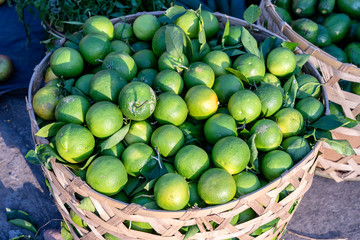Green orange on the bamboo or wooden basket in traditional street market in Ubud, Bali, Indonesia , closeup