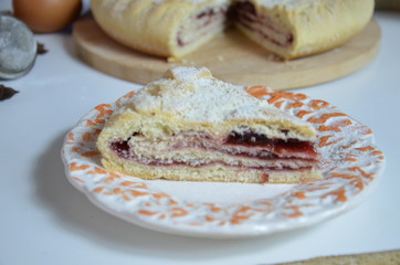 Homemade pie with cherry berries, cup of tea and fork on white wooden table. with ingredients for cooking, cinnamon, anise, icing sugar, topping. homemade baking. copy space. Top view.