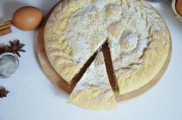 Homemade pie with cherry berries, cup of tea and fork on white wooden table. with ingredients for cooking, cinnamon, anise, icing sugar, topping. homemade baking. copy space. Top view.