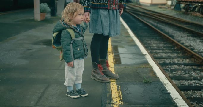 Little toddler and his mother standing on the platfor waiting for a train