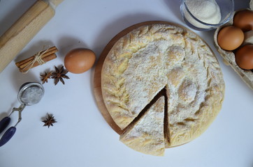 Homemade pie with cherry berries, cup of tea and fork on white wooden table. with ingredients for cooking, cinnamon, anise, icing sugar, topping. homemade baking. copy space. Top view.