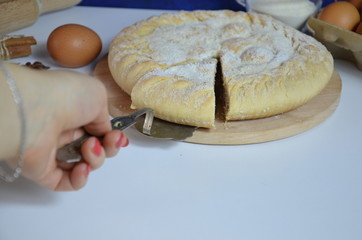 Homemade pie with cherry berries, cup of tea and fork on white wooden table. with ingredients for cooking, cinnamon, anise, icing sugar, topping. homemade baking. copy space. Top view.