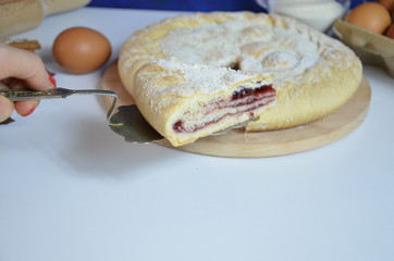 Homemade pie with cherry berries, cup of tea and fork on white wooden table. with ingredients for cooking, cinnamon, anise, icing sugar, topping. homemade baking. copy space. Top view.