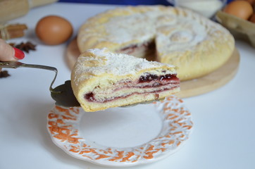 Homemade pie with cherry berries, cup of tea and fork on white wooden table. with ingredients for cooking, cinnamon, anise, icing sugar, topping. homemade baking. copy space. Top view.