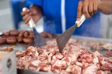 Cuts of pork and beef being cooked at a street food cart in Medellin, Colombia