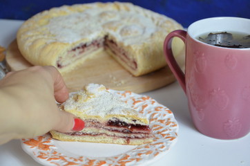 Homemade pie with cherry berries, cup of tea and fork on white wooden table. with ingredients for cooking, cinnamon, anise, icing sugar, topping. homemade baking. copy space. Top view.