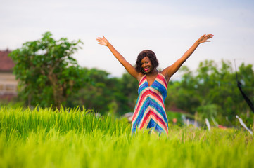 Naklejka na ściany i meble lifestyle portrait of young attractive and happy black African American woman posing cheerful having fun outdoors at beautiful rice field background enjoying holidays trip