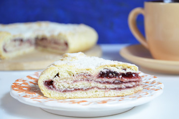 Homemade pie with cherry berries, cup of tea and fork on white wooden table. Top view.