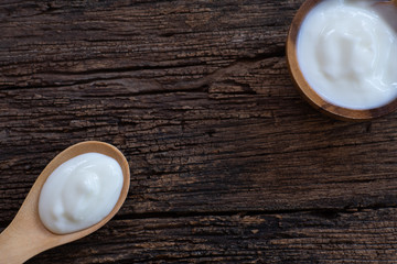 Natural homemade plain organic yogurt in wooden bowl and wood spoon on wood texture background