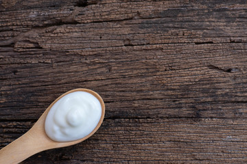 Natural homemade plain organic yogurt in wood spoon on wood texture background