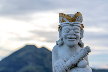 Traditional Balinese sculpture against the background of the volcano Batur on sunrise, morning time. Island Bali, Indonesia. Closeup