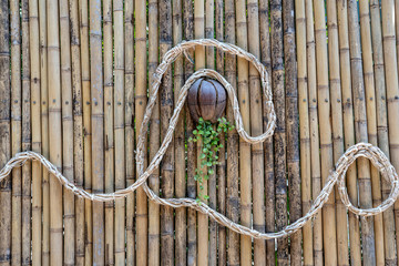Decorated bamboo wall with a rope and a coconut flower pot on a tropical beach in Thailand